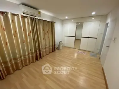 Spacious bedroom with wooden flooring and large mirrored wardrobe