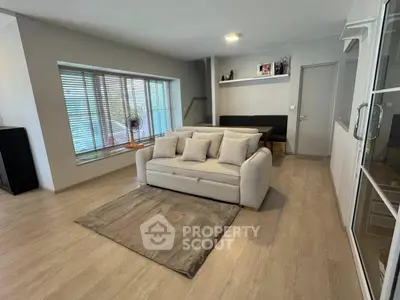 Spacious modern living room with cozy sofa and large window, perfect for relaxation and entertaining.