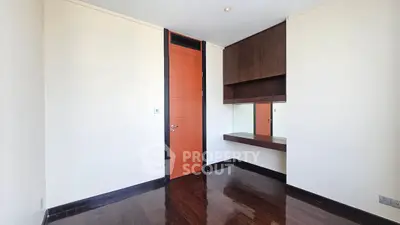 Minimalist room with wooden flooring and built-in desk, ideal for a study or small office space.