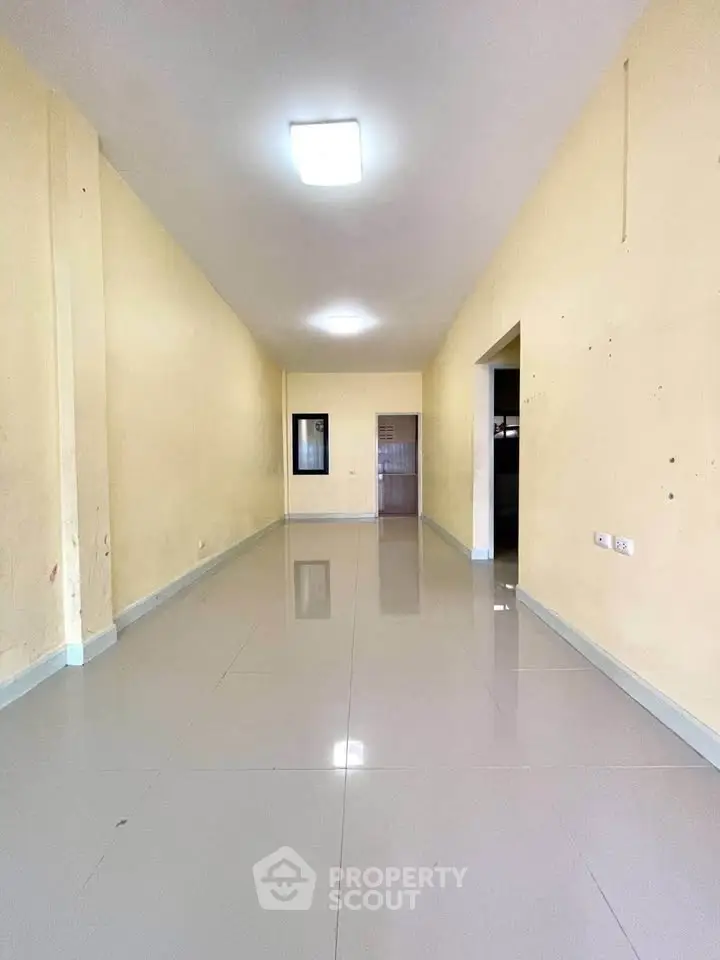 Spacious empty room with glossy tiled flooring and neutral walls, ideal for customization.