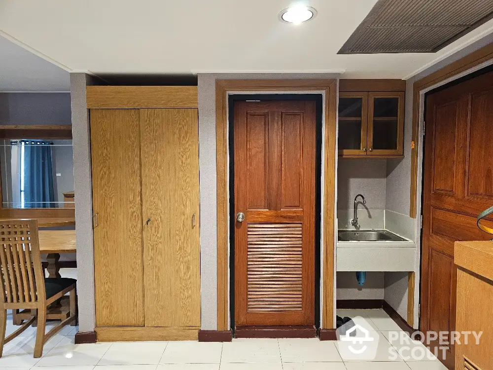 Cozy interior with wooden doors and dining area, featuring a compact kitchenette and ample storage space.