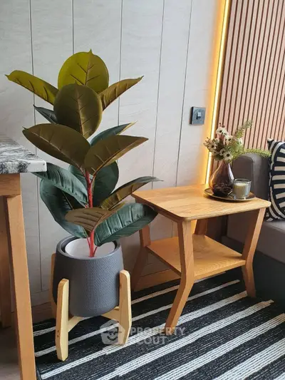 Stylish modern living room corner with wooden side table, decorative plant, and cozy seating area.