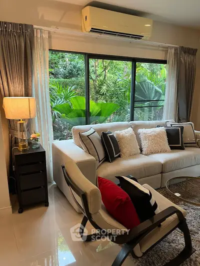Stylish living room with large window and lush garden view, featuring modern furniture and elegant decor.
