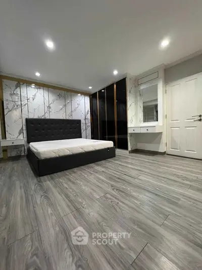 Spacious modern bedroom with elegant flooring and stylish wall design, featuring a comfortable bed and built-in wardrobe.