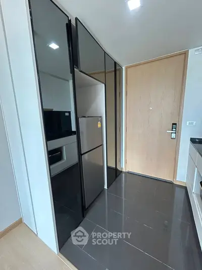 Modern kitchen with sleek black cabinets and stainless steel appliances in a compact layout.