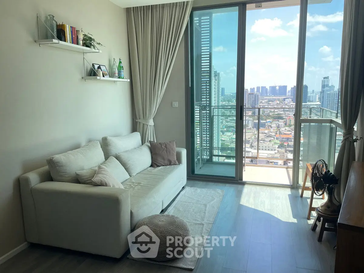 Modern living room with balcony and city view, featuring cozy sofa and stylish decor.