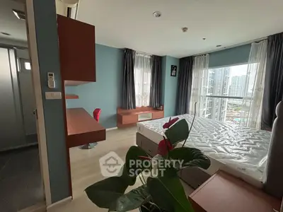 Modern bedroom with large windows and city view, featuring a desk and stylish decor.