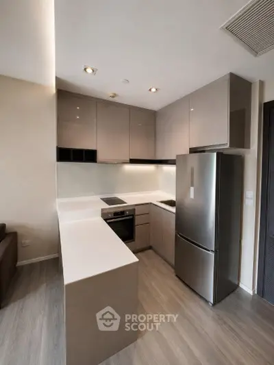 Modern kitchen with sleek cabinetry and stainless steel appliances in a contemporary apartment.