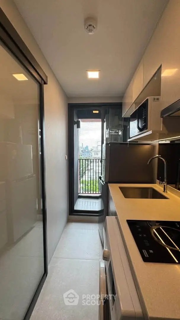 Modern kitchen with sleek appliances and balcony view in urban apartment