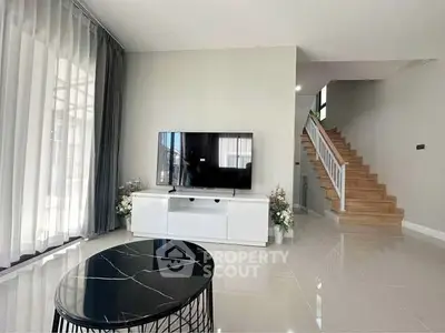 Modern living room with sleek TV setup and elegant staircase