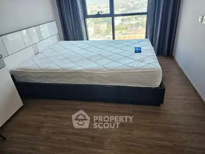 Modern bedroom with large window and city view, featuring a comfortable bed and sleek flooring.