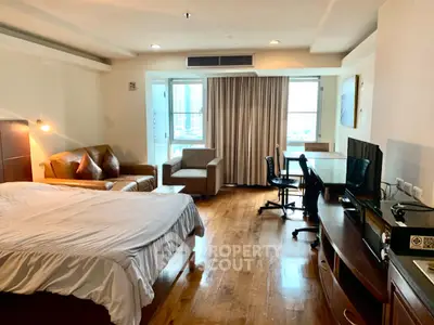 Spacious studio apartment with modern furnishings and large window view.