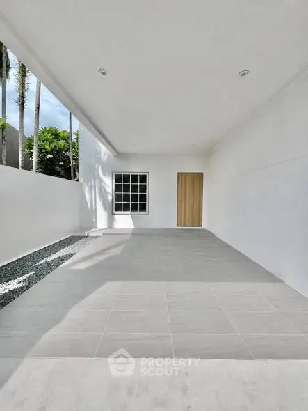Spacious minimalist patio with tiled flooring and garden view, perfect for relaxation and outdoor activities.