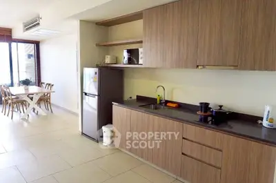 Modern kitchen with sleek cabinetry and dining area in open layout apartment.