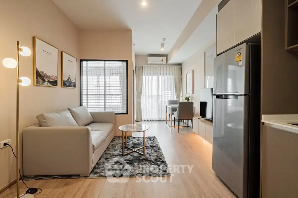 Modern living room with stylish decor and open layout, featuring a cozy sofa and sleek kitchen area.