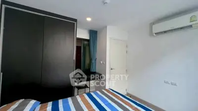 Modern bedroom with striped bedding, dark wardrobe, and air conditioning unit.