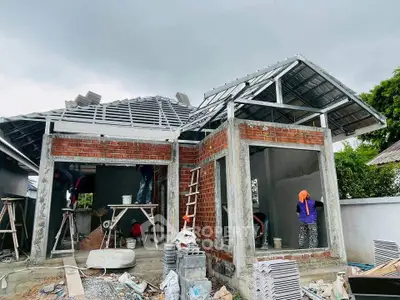 Under-construction house with exposed brick and metal roofing, showcasing modern architectural design.