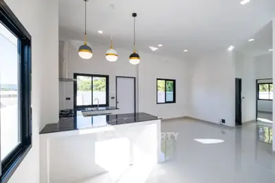 Modern open-plan kitchen with sleek black countertops and pendant lighting in a bright, spacious interior.