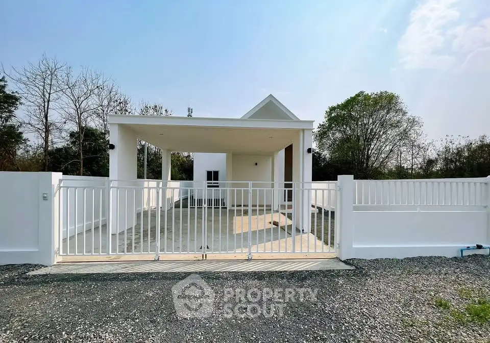 Modern white house with spacious driveway and gated entrance in a serene setting.