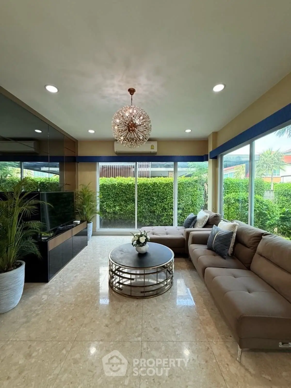 Elegant living room with modern decor and large windows overlooking lush greenery.