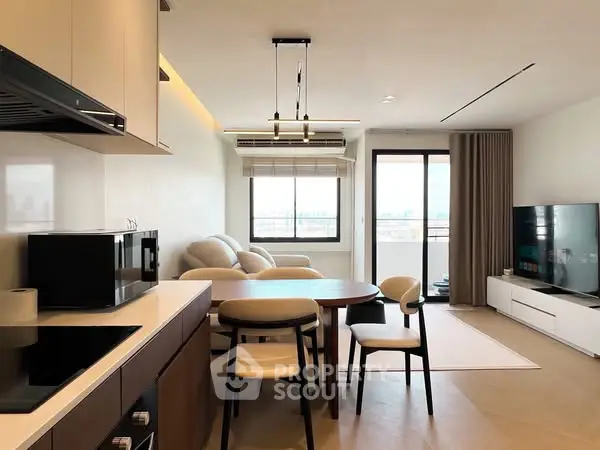 Modern open-plan living room with kitchen, featuring sleek furniture and large window with city view.