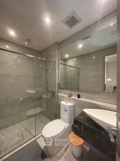 Modern bathroom with glass shower and sleek fixtures in luxury apartment