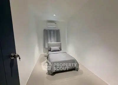 Minimalist bedroom with single bed and air conditioning in modern apartment.