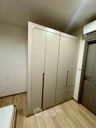 Modern bedroom with sleek wardrobe and air conditioning unit, showcasing minimalist design and functionality.