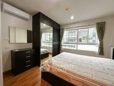 Spacious bedroom with large windows and modern furnishings in a bright apartment.