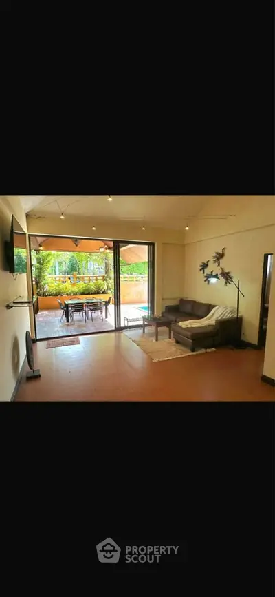 Spacious living room with open layout leading to a large balcony with garden view.