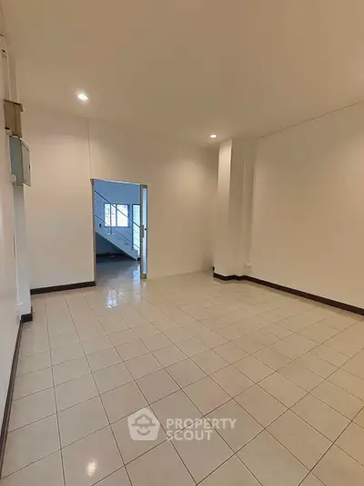 Spacious empty room with tiled flooring and bright lighting, ideal for customization.