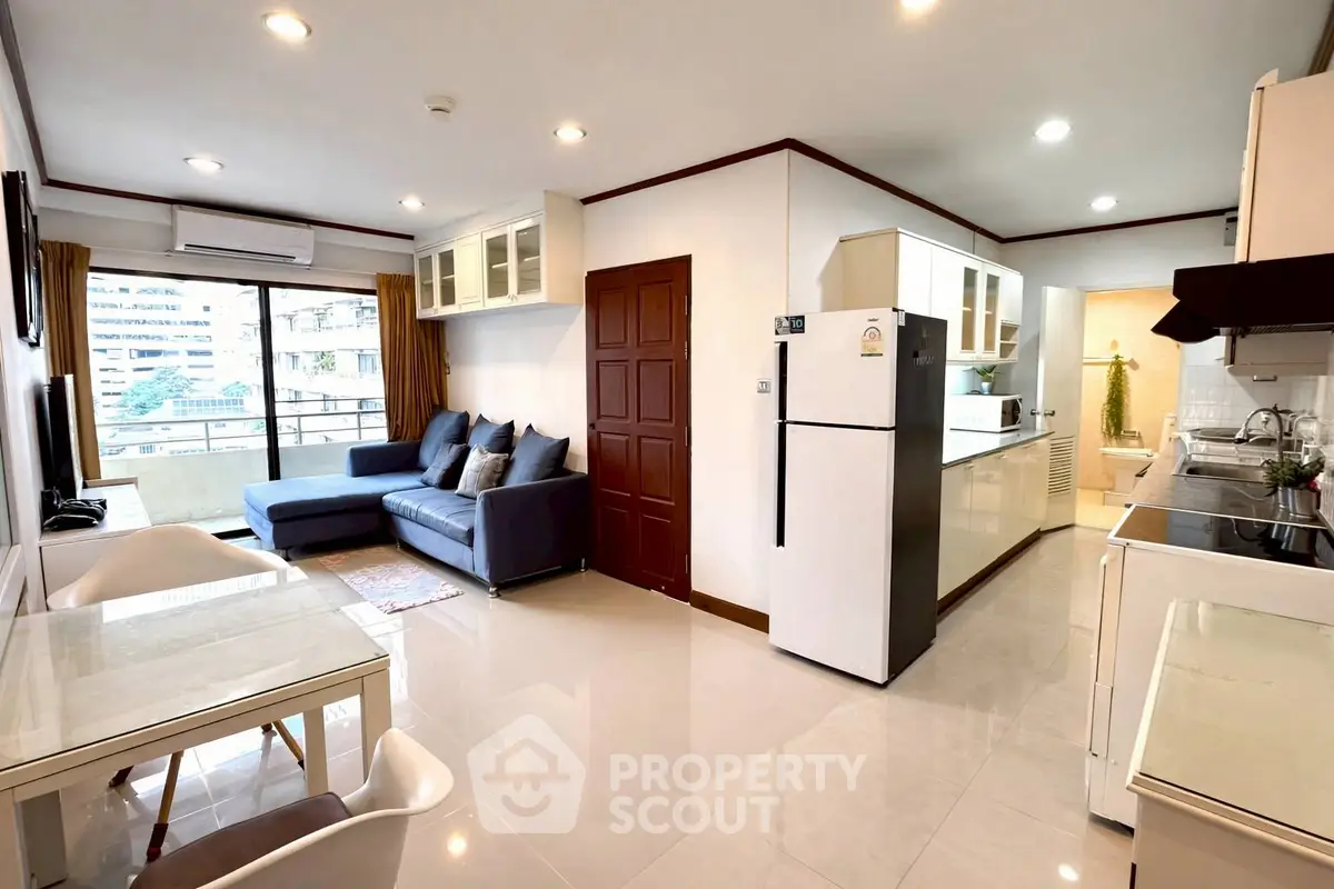 Spacious open-plan living room with modern kitchen and balcony view in urban apartment.
