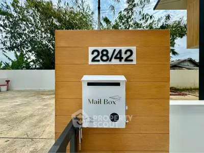 Modern mailbox on wooden panel with house number in contemporary residential area