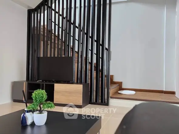 Modern living room with stylish staircase and sleek TV stand, perfect for contemporary living.