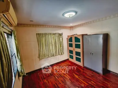 Spacious bedroom with wooden flooring and ample natural light