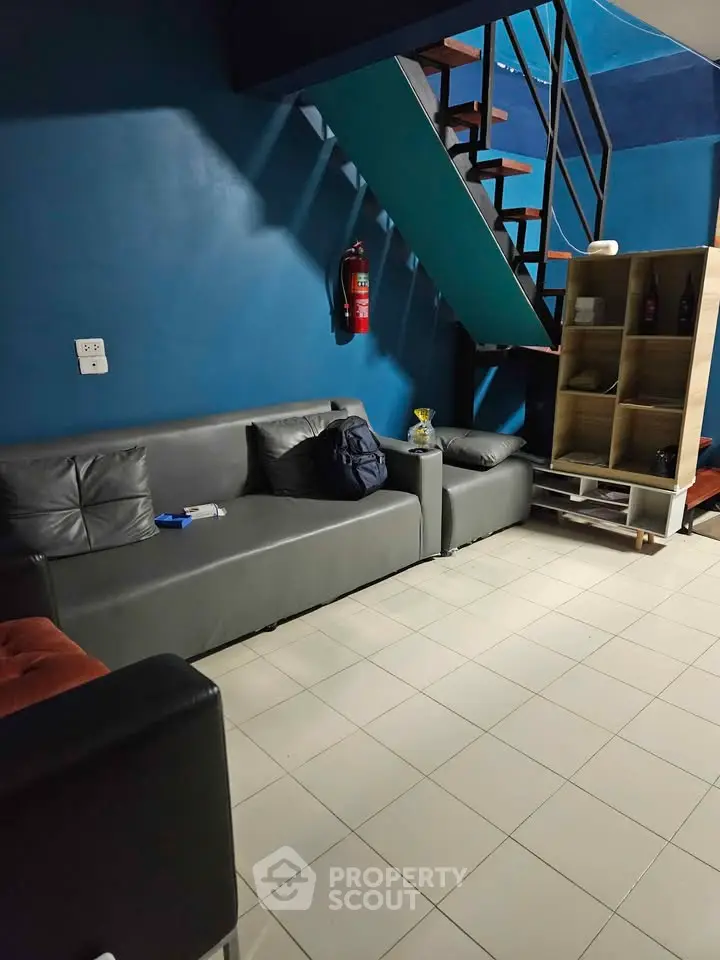 Modern living room with blue walls, stylish staircase, and cozy seating area.