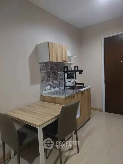 Cozy kitchen with modern wooden cabinets and dining area in compact apartment.