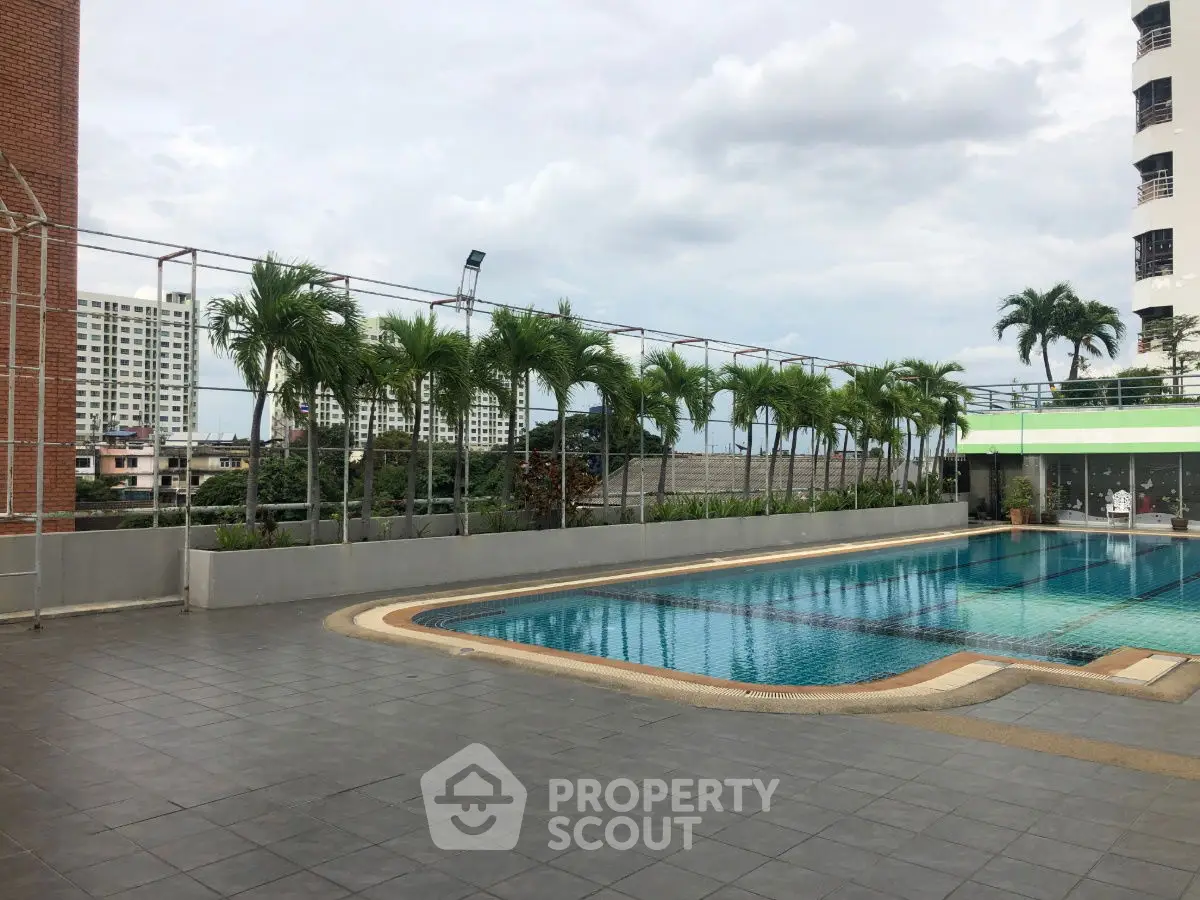 Luxurious rooftop pool with city view and palm trees, perfect for relaxation.