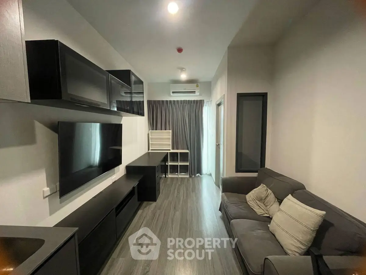 Modern living room with sleek furniture and large TV, featuring a cozy sofa and stylish decor.