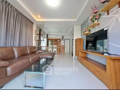 Spacious modern living room with leather sofa and large TV, perfect for relaxation and entertainment.