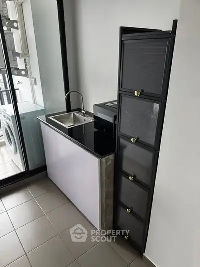 Compact kitchen area with modern sink and storage cabinets in a sleek apartment.
