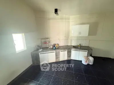 Spacious kitchen with modern cabinetry and sleek black tile flooring