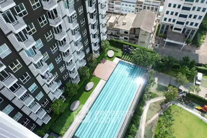 Stunning aerial view of modern apartment complex with large swimming pool and lush greenery.
