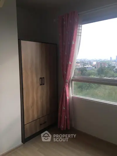 Cozy bedroom corner with wardrobe and city view through window.