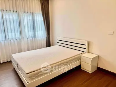 Spacious bedroom with modern white bed and natural light.