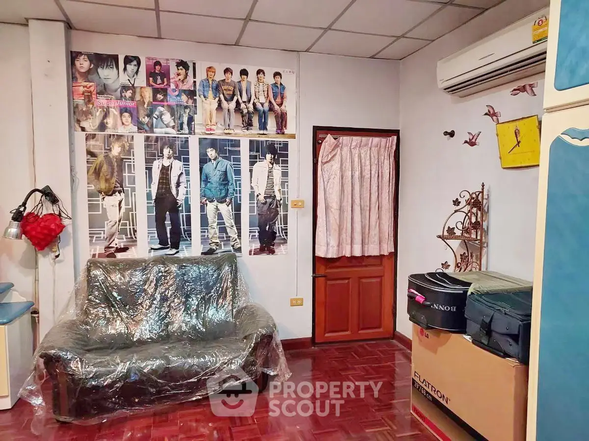 Cozy living room with air conditioning and stylish decor, featuring a sofa and vibrant wall posters.