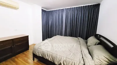 Cozy bedroom with elegant curtains and wooden flooring, featuring a comfortable bed and air conditioning.