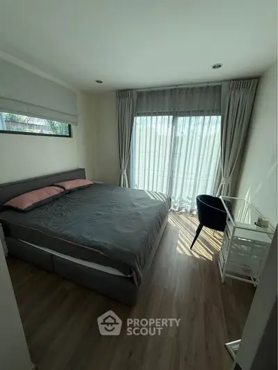 Cozy bedroom with large window and modern furnishings, perfect for relaxation and comfort.