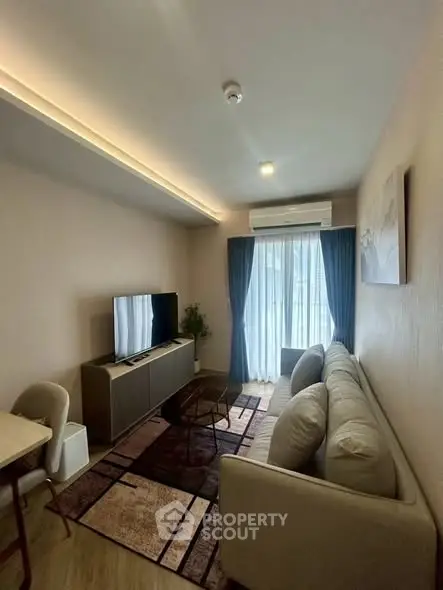 Modern living room with cozy sofa, TV, and natural light from large window.