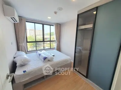 Bright and cozy bedroom with large window and modern wardrobe, perfect for urban living.